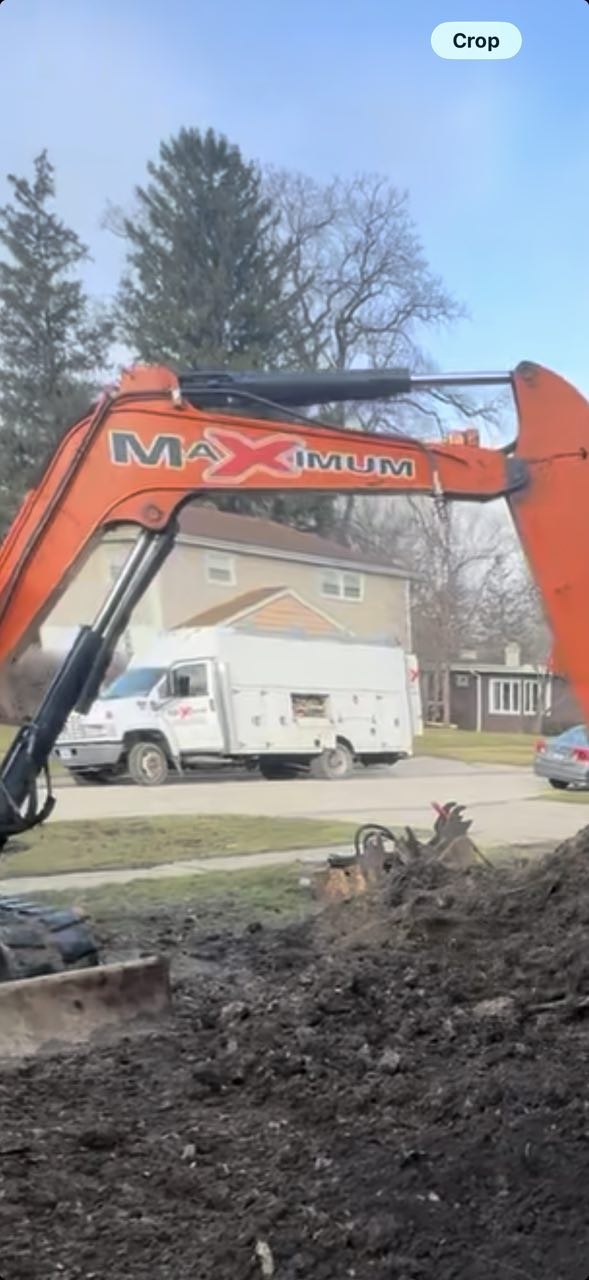 Orange Maximum-branded excavator at residential trench dig